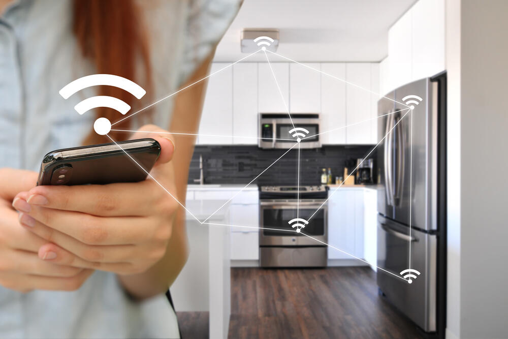 A woman controls kitchen smart appliances with a smartphone. Such internet-connected devices are part of what’s called the internet of things (IoT).