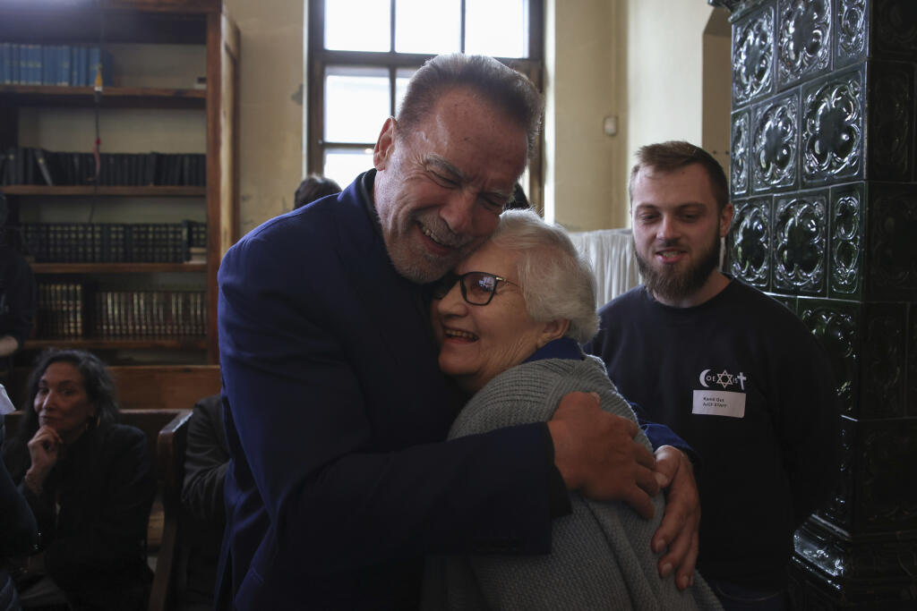 Arnold Schwarzenegger, left, hugs Holocaust survivor Lydia Maksimovicz, right, in Oswiecim, Poland, Wednesday, Sept. 28, 2022. Film icon Arnold Schwarzenegger visited the site of the Nazi German death camp Auschwitz on Wednesday to send a message against hatred. The "Terminator" actor was given a tour of the site, viewing the barracks watchtowers and the remains of gas chambers that endure as evidence of the German extermination of Jews, Roma and others during World War II. (AP Photo/Michal Dyjuk)