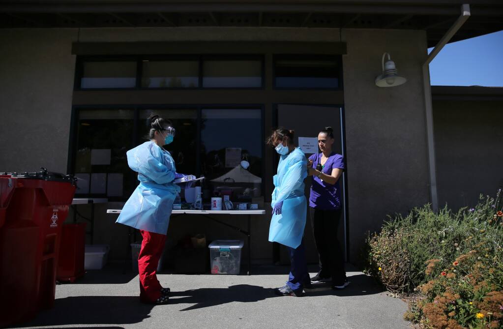 (From left) Registered nurses Sandra Castano and Nicole Garcia suit up with help from Rachael Lopez as they prepare to walk through the Sauvignon Village student housing complex and check on some of the temporary residents quarantining from COVID-19 on the Sonoma State University campus in Rohnert Park, California, on Sunday, July 5, 2020. (Beth Schlanker/The Press Democrat)