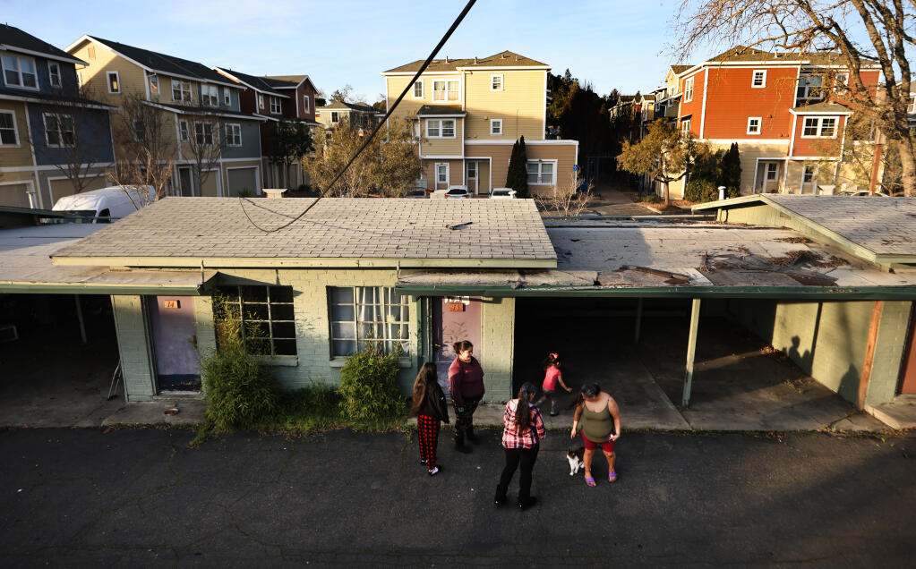 Gold Coin residents from left clockwise, Gloria Martinez, Aileen Castillo, Valentina Castillo, 4, and Marisella Nunez visit a neighbor just before sunset. The Gold Coin was purchased by St. Vincent DePaul and former Santa Rosa City Council member Jack Tibbetts in 2019, on Mendocino Avenue in Santa Rosa, Friday, Jan. 21, 2022. Surrounding the old hotel are newer condos and apartments to the north, background, and a Safeway shopping center to the south. (Kent Porter / The Press Democrat)
