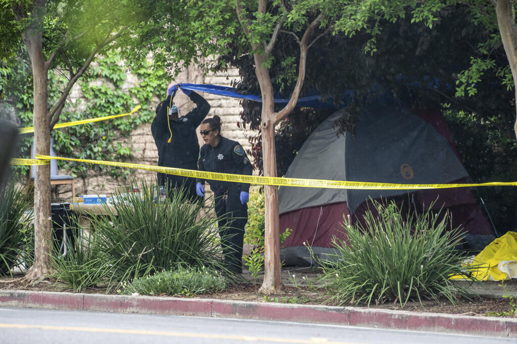 Police investigate the site where a homeless woman was stabbed several times through the side of her tent near Second and L streets in Davis, Calif., Tuesday, May 2, 2023. Residents of the Northern California university town are on edge after three people were stabbed within a week, including two fatally. (Hector Amezcua/The Sacramento Bee via AP)