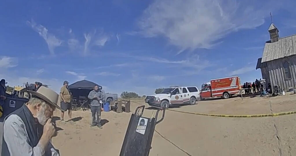 In this image from video released by the Santa Fe County Sheriff's Office, Alec Baldwin, left, smokes a cigarette while waiting to speak with investigators following a fatal shooting last year on a movie set in Santa Fe, New Mexico. Law enforcement officials have released a trove of video and photographic evidence in the investigation of a fatal October shooting of a cinematographer by actor and producer Alec Baldwin on the set of a Western movie. Data files released by the Santa Fe County Sheriff's Office on Monday, April 25, 2022, included videos of investigators debriefing Baldwin on the day of the shooting inside a compact office. (Santa Fe County Sheriff's Office via AP)