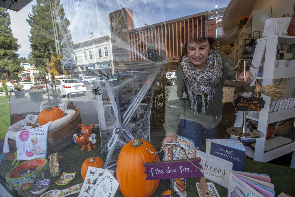 Artist Valerie Marota places her hand made Halloween decorations into “The Store Next Door” front window Halloween centerpiece display along Fourth Street in downtown Santa Rosa on Monday, Oct. 17, 2022. (Chad Surmick / The Press Democrat)