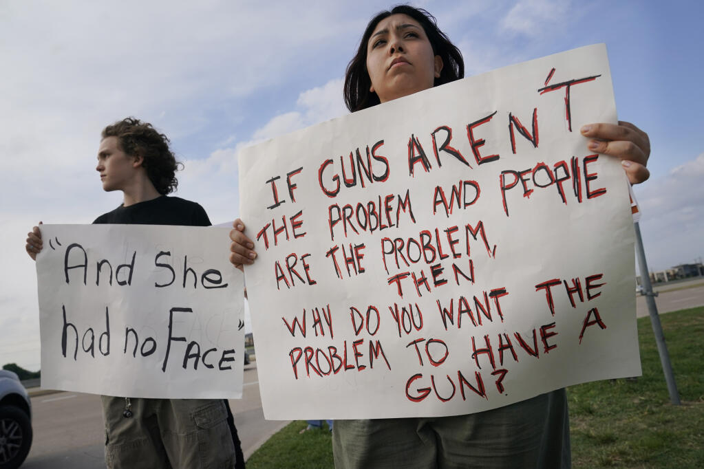 Sam Morin, 17, right, and Briason Foley, 15, hold protest signs outside a prayer vigil after a mass shooting the day before Sunday, May 7, 2023, in Allen, Texas. (AP Photo/LM Otero)
