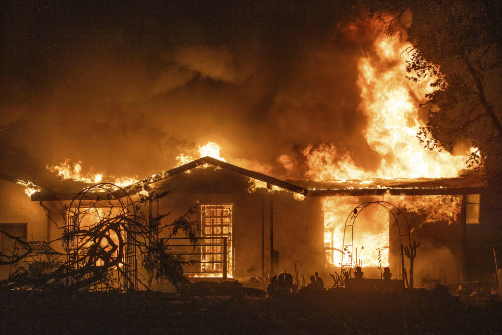 FILE - A house burns on Platina Road at the Zogg Fire near Ono, Calif., on Sep. 27, 2020. California utility regulators on Tuesday, Oct. 25, 2022, proposed penalizing Pacific Gas & Electric more than $155 million in fines for its role in starting the 2020 Zogg Fire in Shasta County that destroyed hundreds of homes and left four people dead. (AP Photo/Ethan Swope, File)